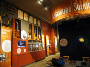 A museum exhibit explains that Orville Gibson founded his mandolin and guitar manufacturing company in Kalamazoo in 1902